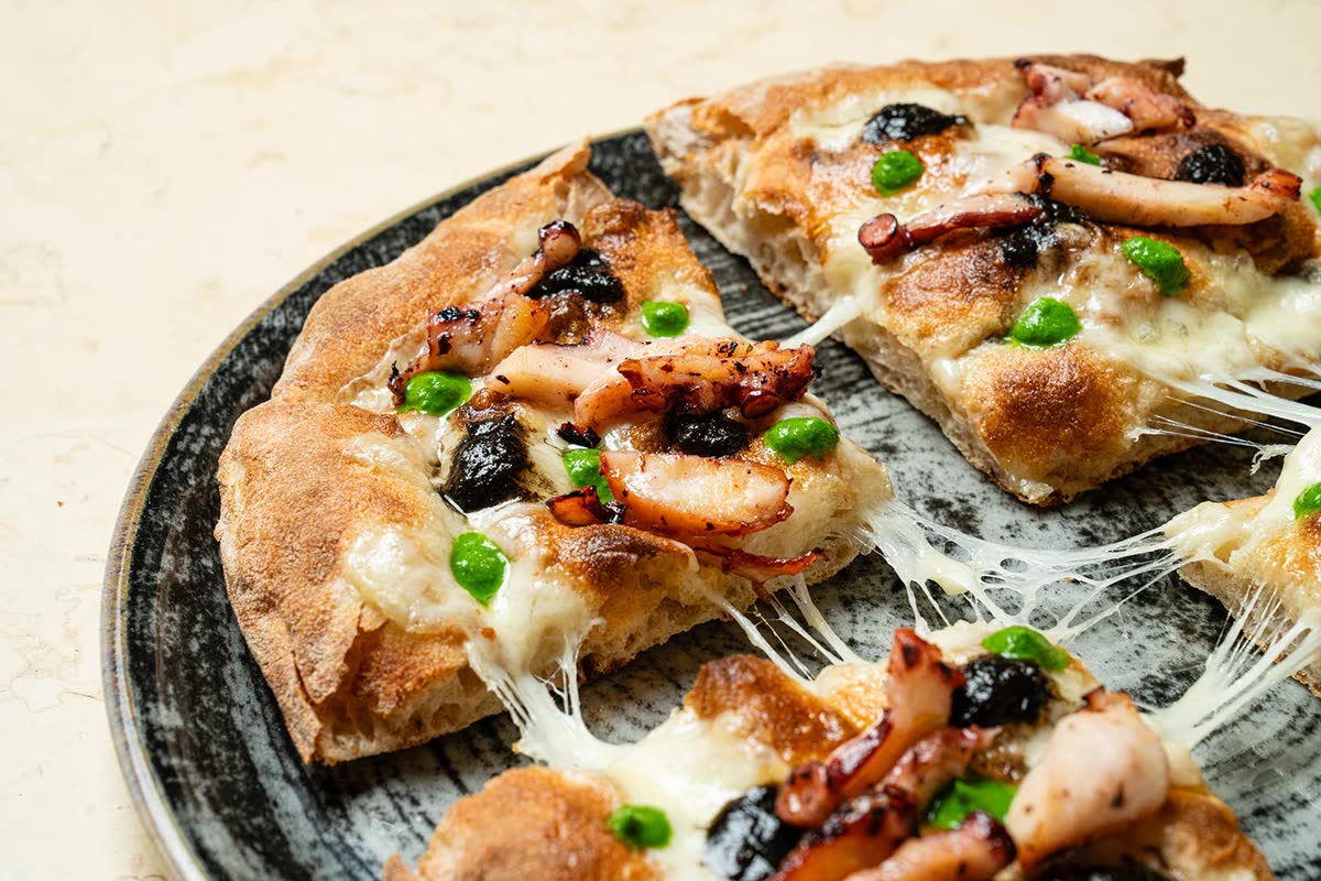 Pizza di Catello servita su piatto di ceramica scura